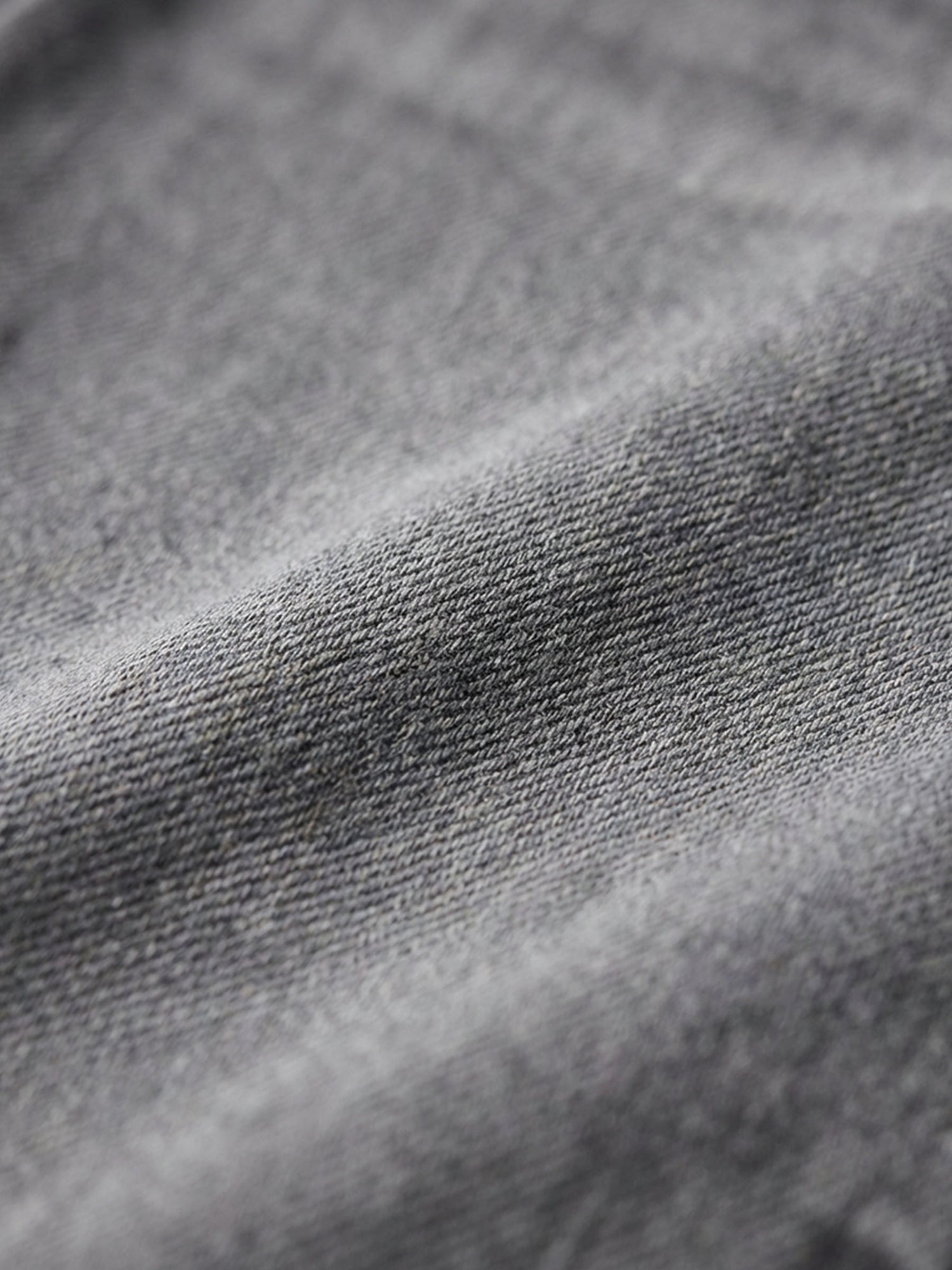 Close-up of grey denim fabric showing soft texture and washed finish.