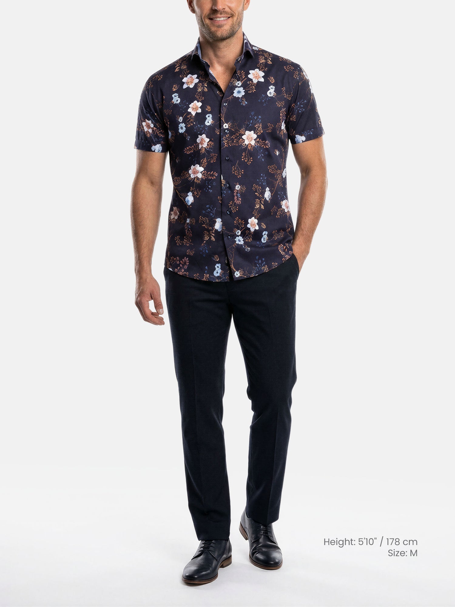 Model wearing navy floral print men’s shirt with tailored fit and dark trousers