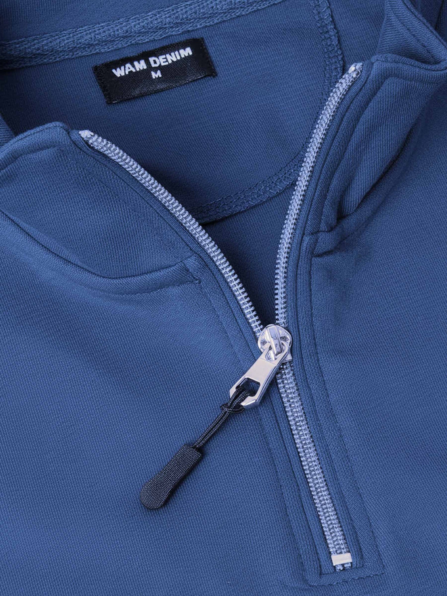 Close-up of indigo quarter-zip sweater showing zipper detail and smooth fabric.