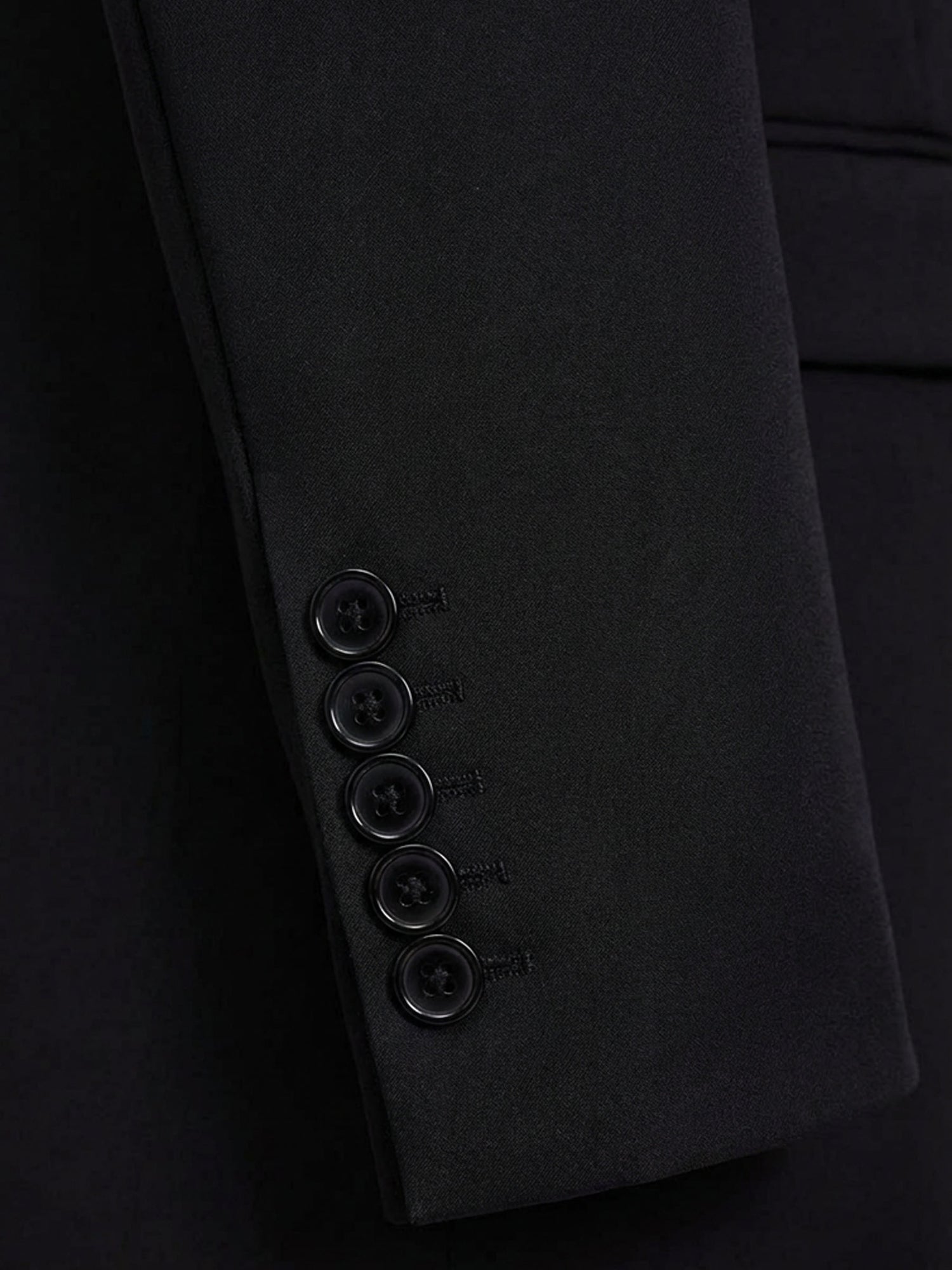 Close-up of black suit blazer sleeve with five-button cuff detail.