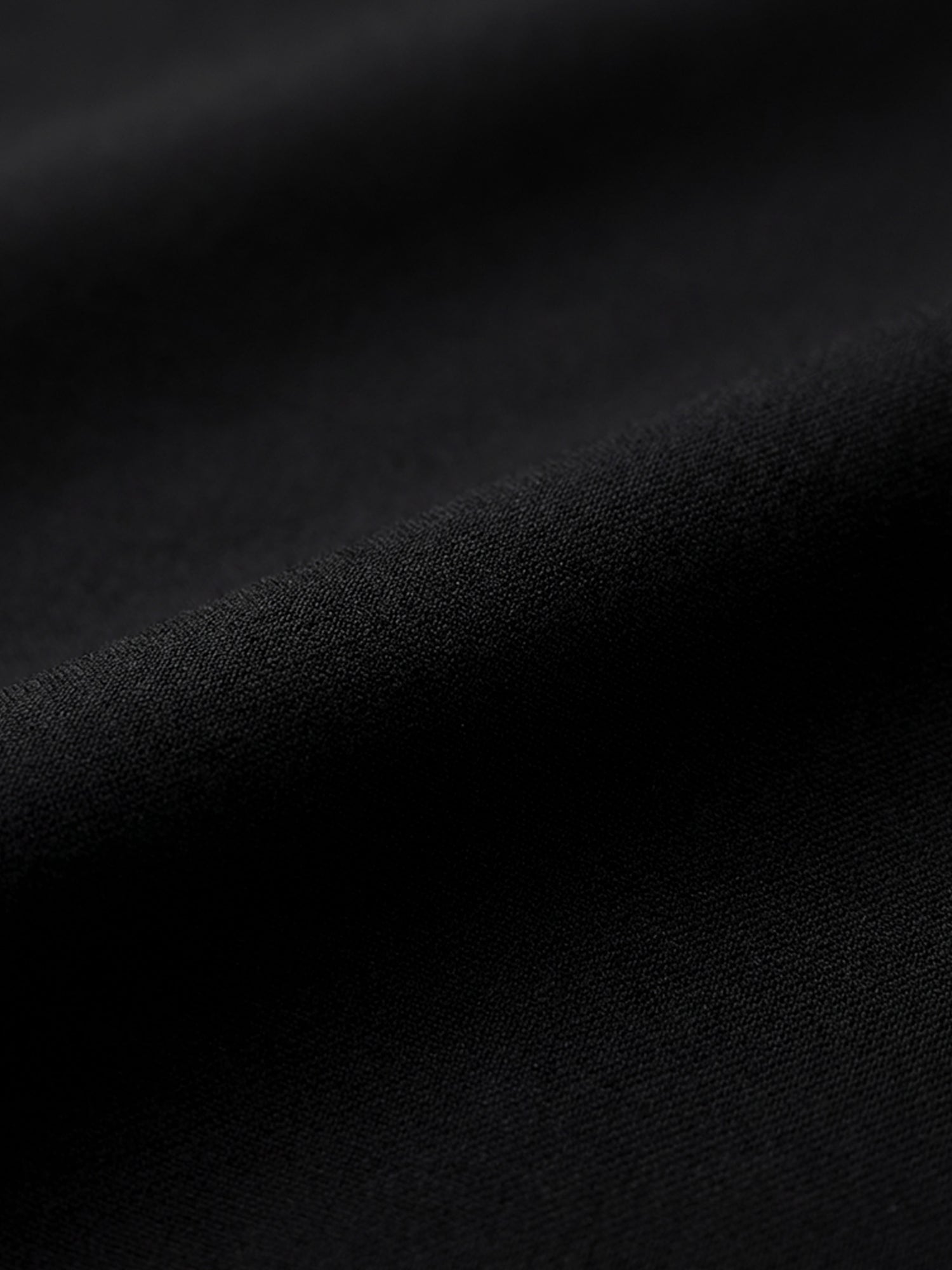 Close-up of black suit blazer fabric showing smooth, refined texture.