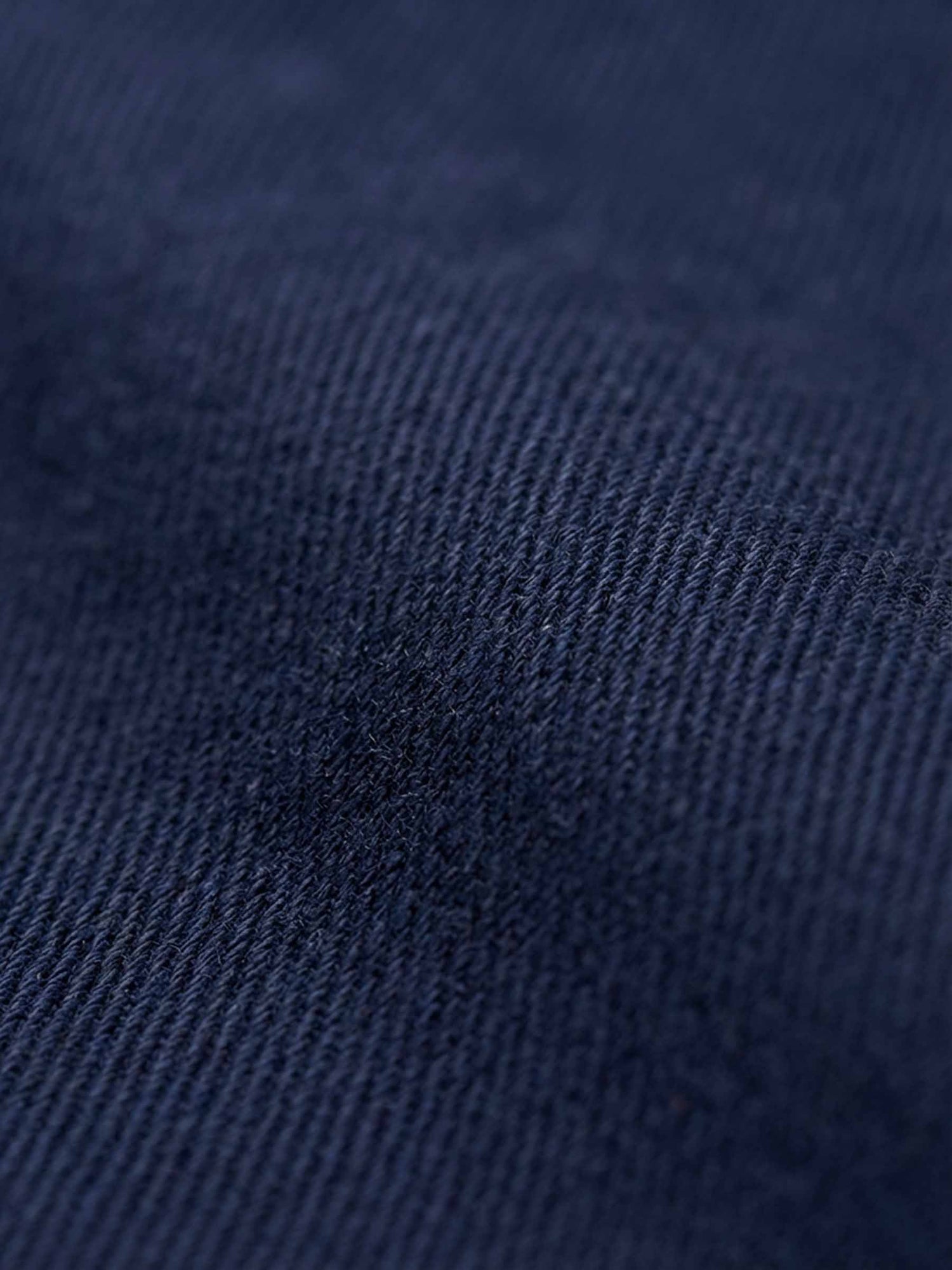 Close-up of navy denim fabric showing smooth weave and premium texture