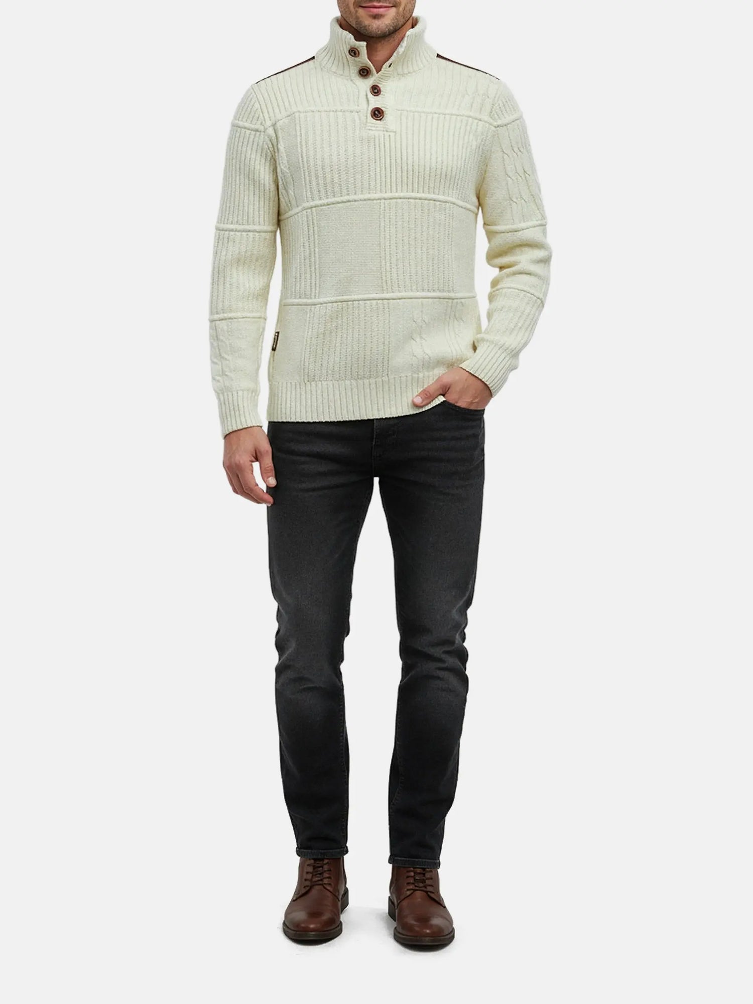 Full-body view of a man wearing an off-white textured knit sweater with dark jeans.