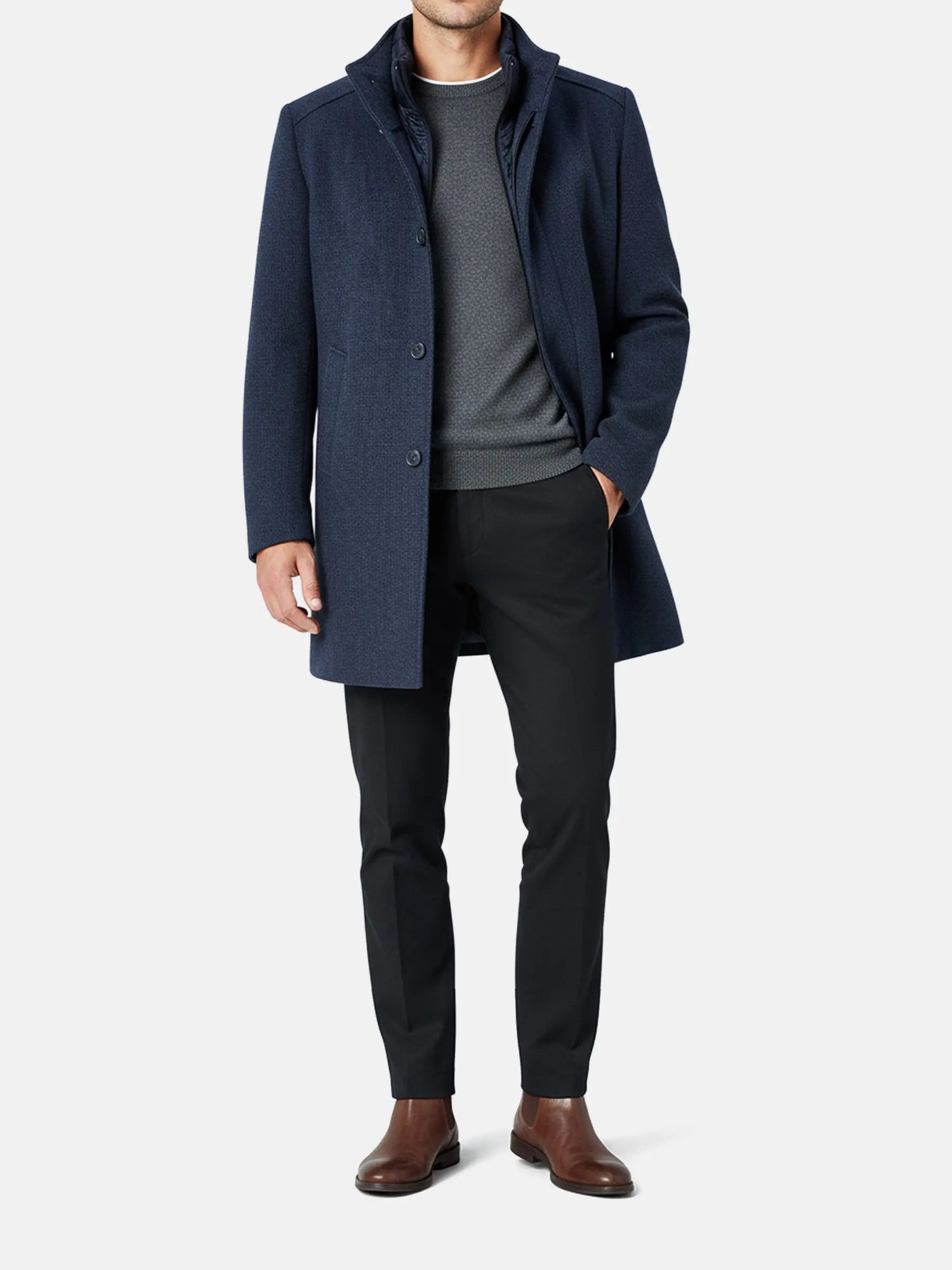 Full-body view of a man wearing a light navy trenchcoat styled with dark trousers.