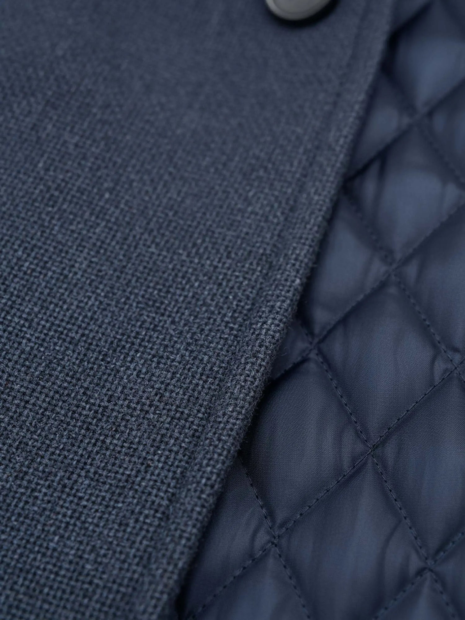 Close-up of light navy trenchcoat fabric showing textured outer weave and quilted inner lining.