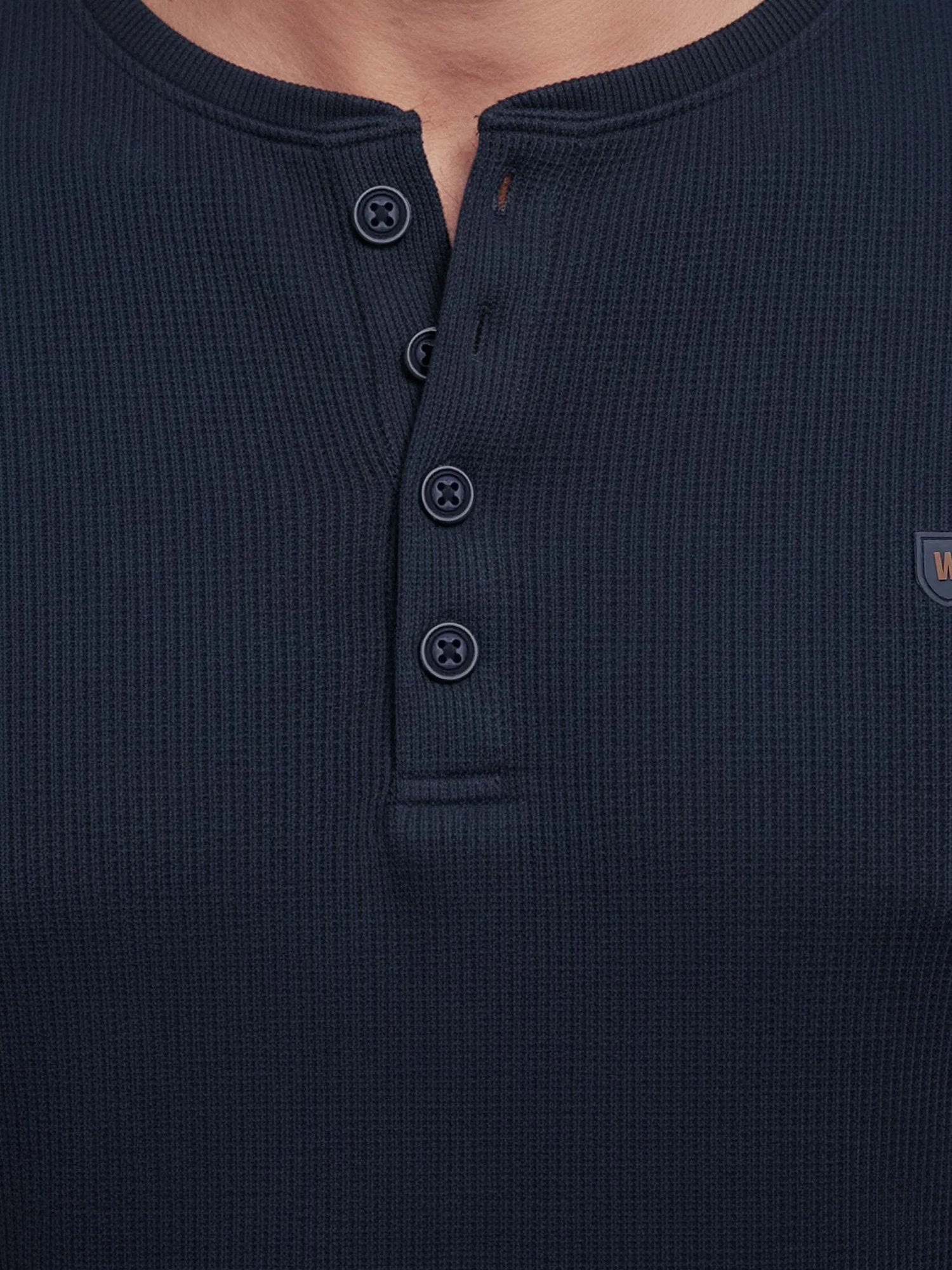 Close-up of navy Zest sweater buttons and textured knit fabric.