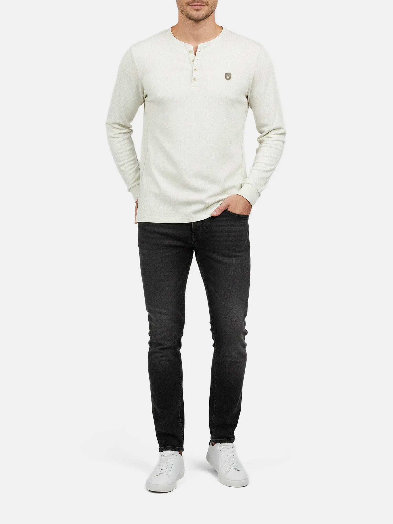 Model wearing off-white sweater with long sleeves, styled with dark jeans.