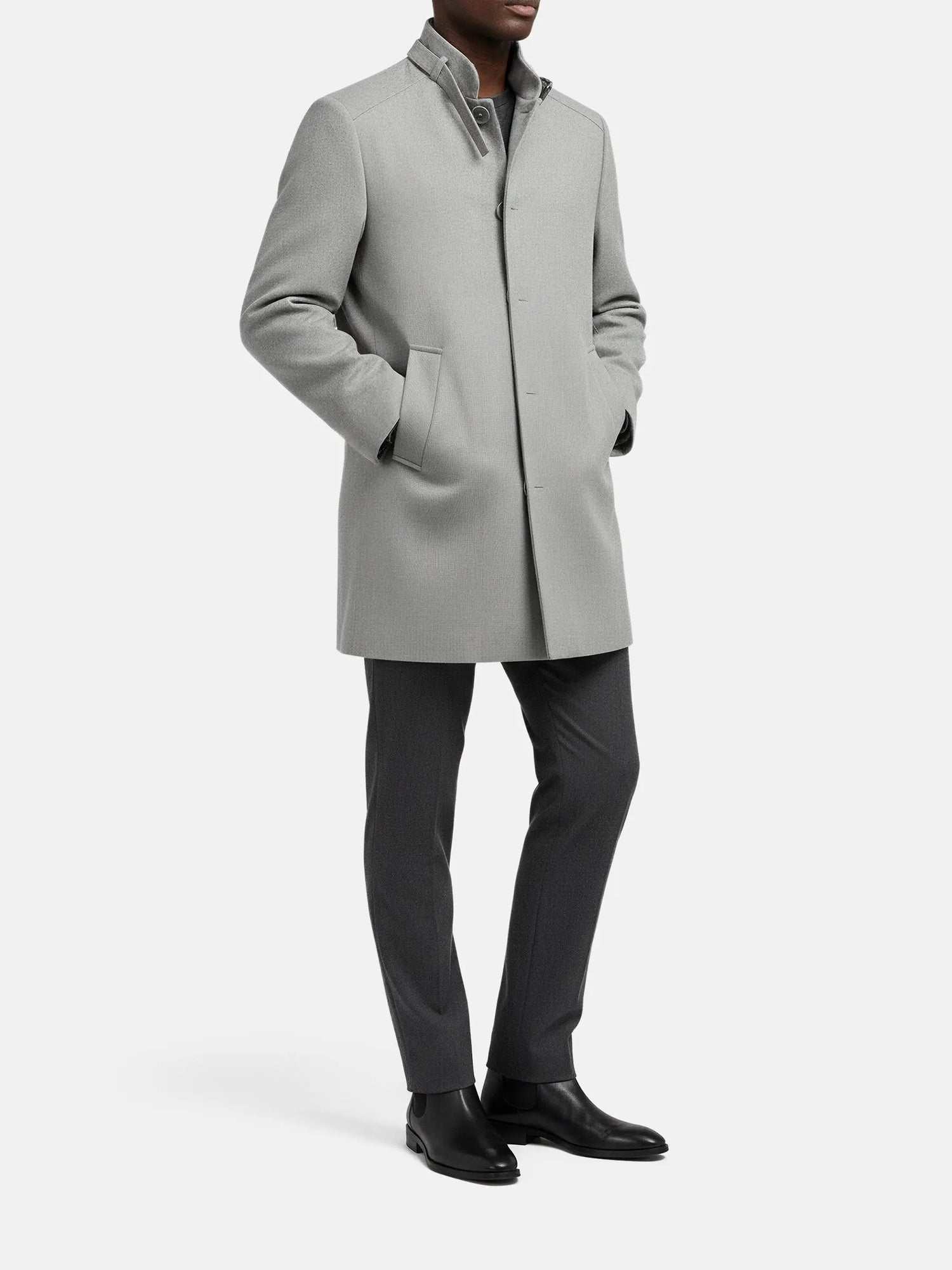 Full-body view of grey trenchcoat styled with dark trousers and black dress boots.