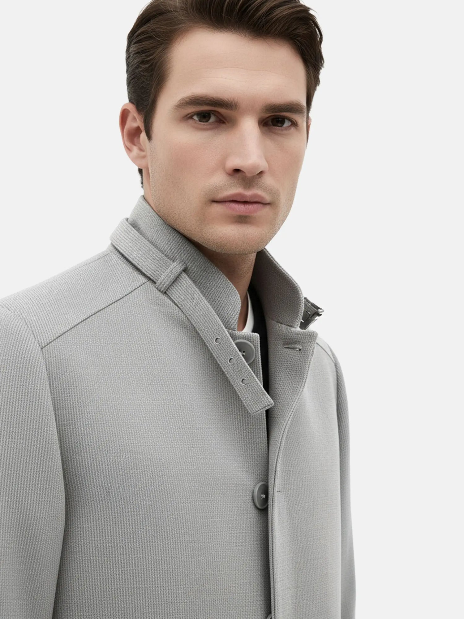 Close-up of grey trenchcoat collar showcasing textured fabric and button details.