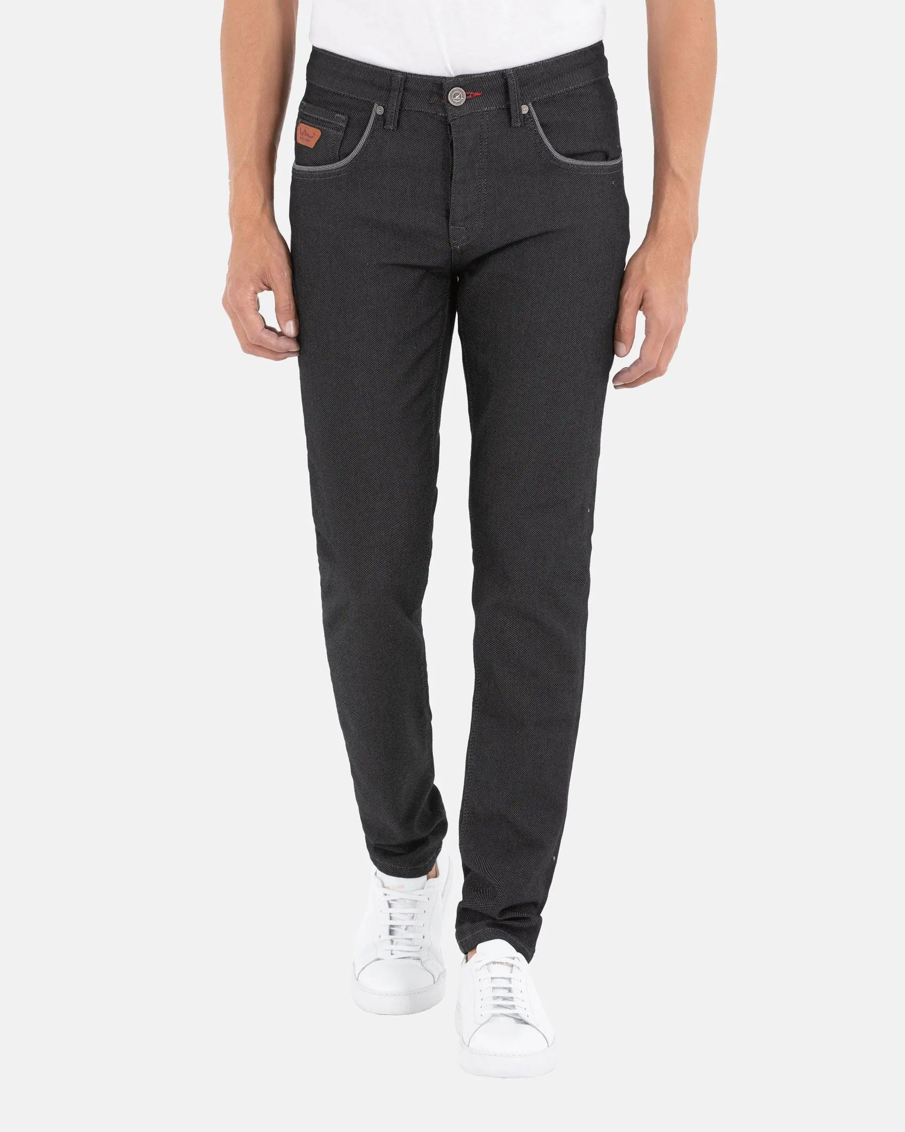 Man wearing slim-fit black patterned jeans with white sneakers and contrast stitching – Wam Denim.