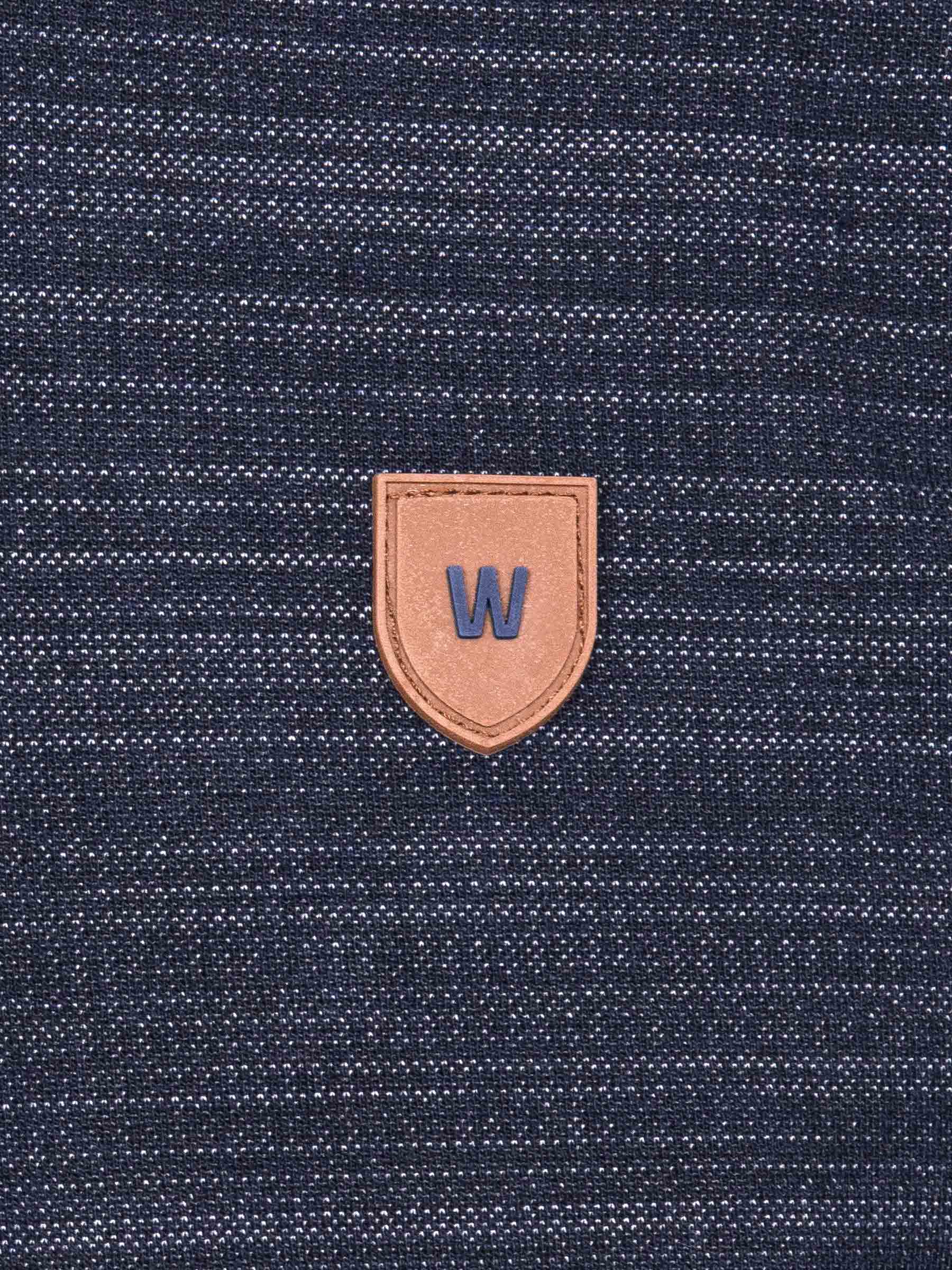Close-up of a textured blue fabric with a brown leather patch featuring a 'W' logo.