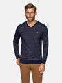 Man wearing a navy striped long-sleeve sweater with a small logo on a white background