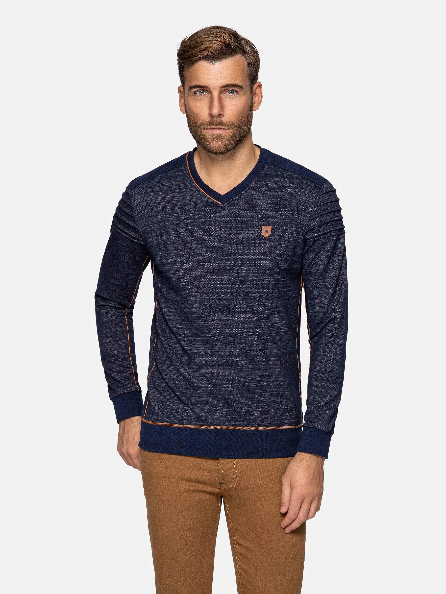 Man wearing a navy striped long-sleeve sweater with a small logo on a white background