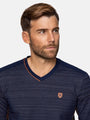 Man wearing a navy sweater with a small logo on a light gray background