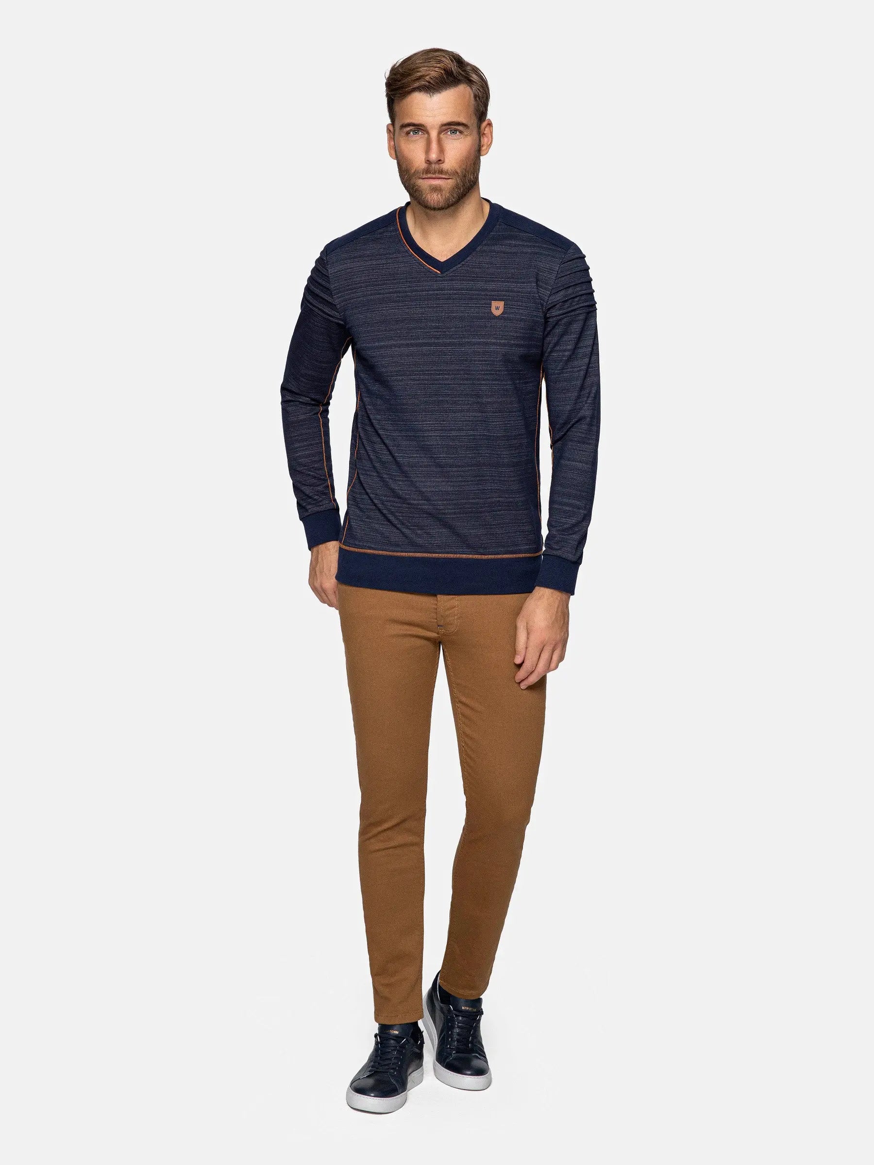 Man wearing a navy striped sweater and brown pants on a white background