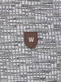 Close-up of the W-shield logo on the grey textured knit fabric – Wam Denim.