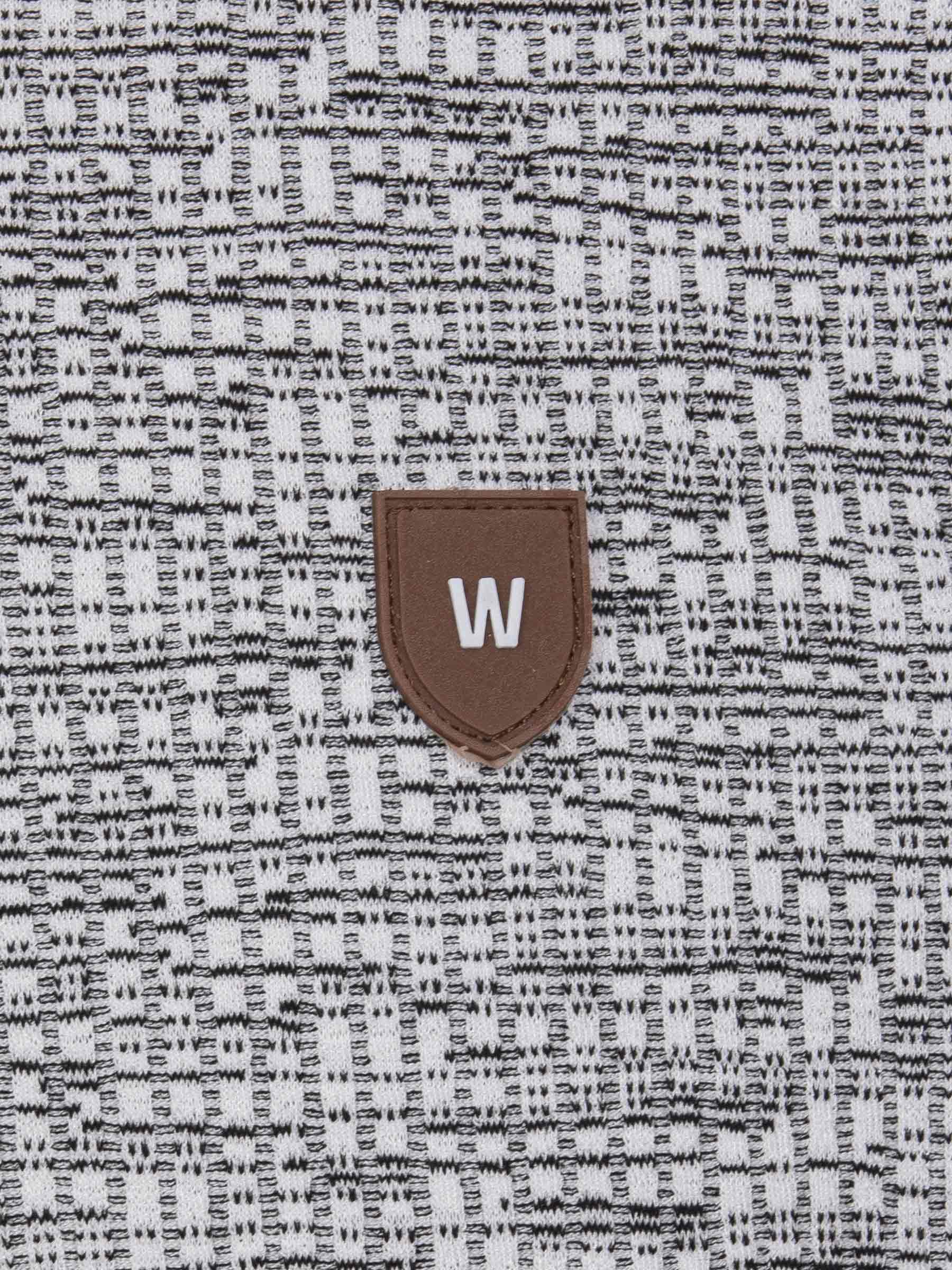 Close-up of the W-shield logo on the grey textured knit fabric – Wam Denim.