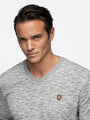 Close-up portrait of a man in a grey V-neck sweater – Wam Denim.