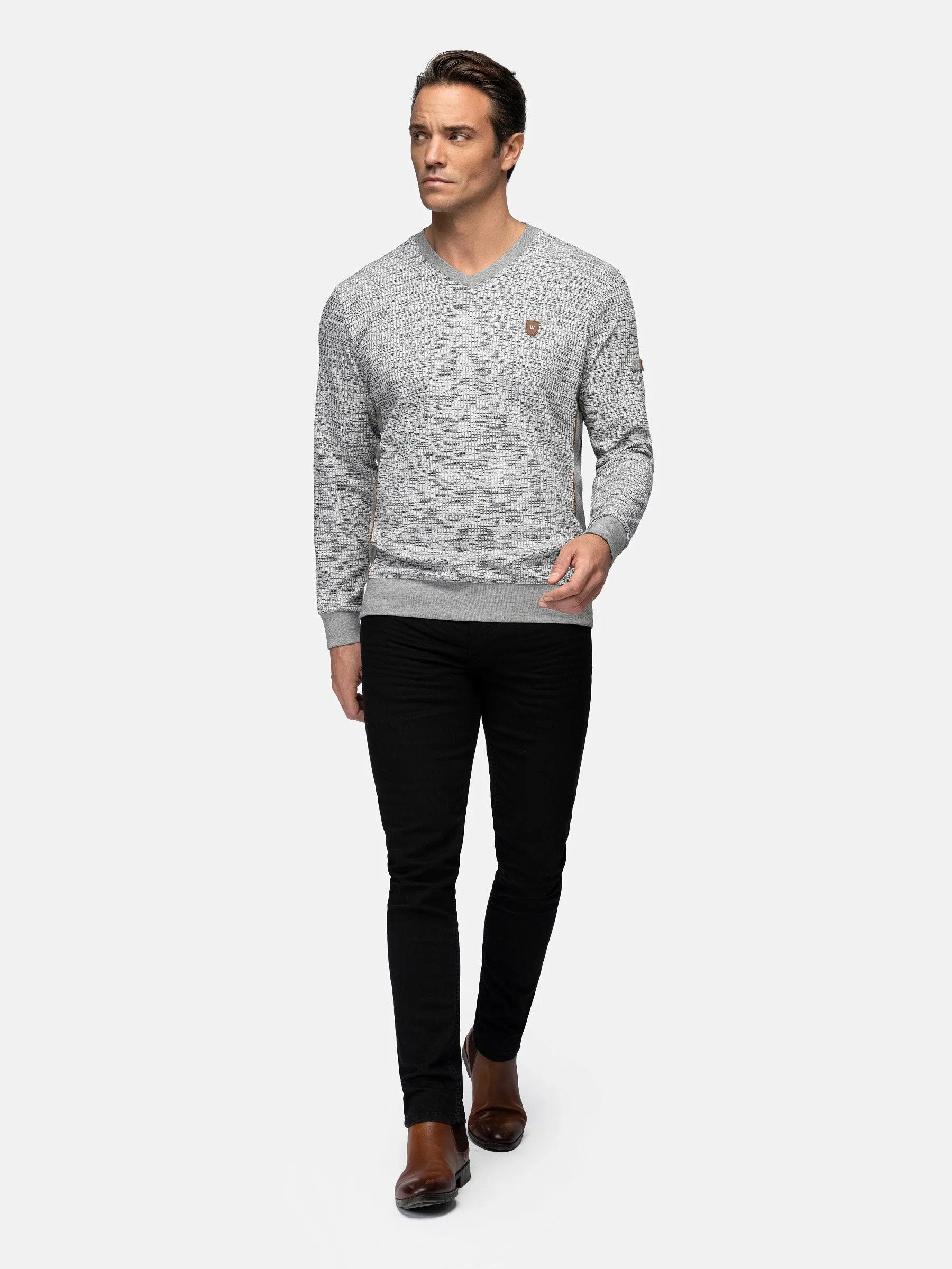 Full shot of a man wearing a grey V-neck sweater and black jeans – Wam Denim.