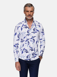 Man wearing white long-sleeve floral print shirt with blue leaf pattern and dark trousers – Wam Denim.