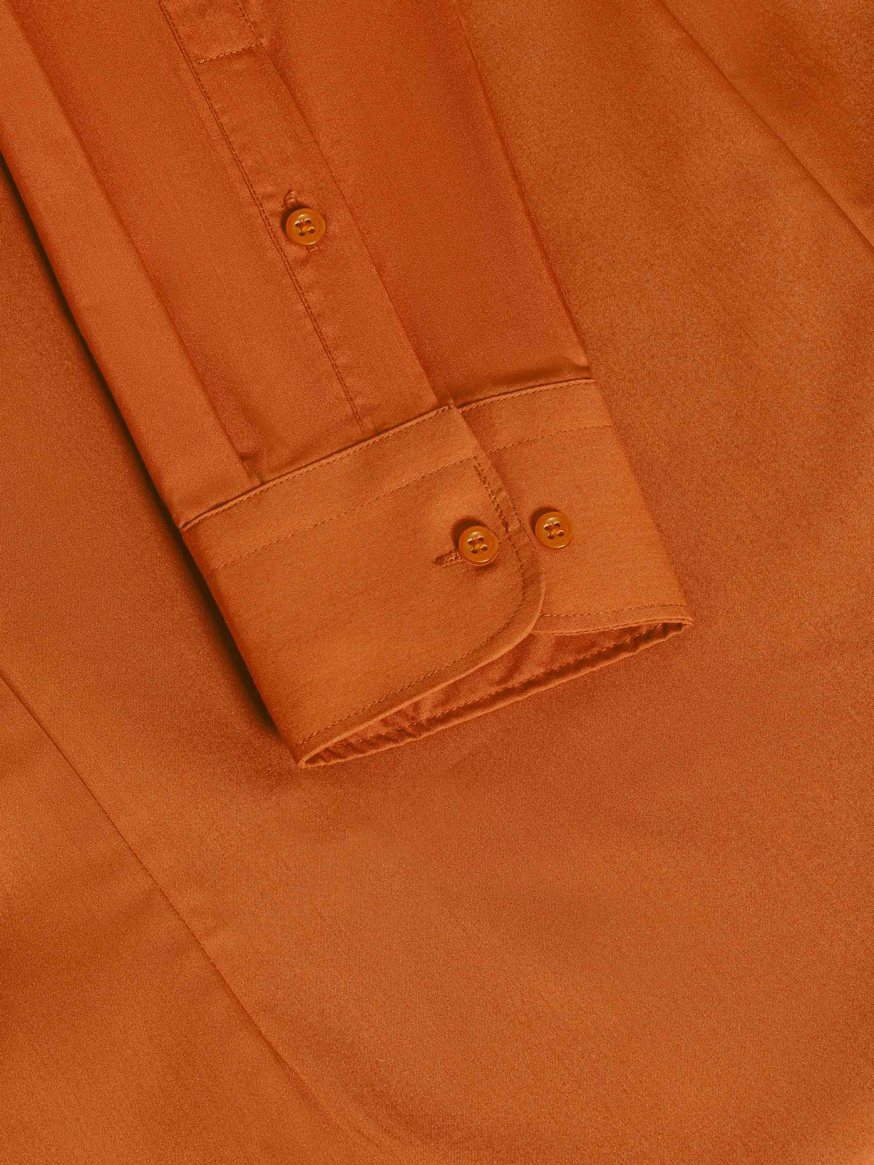 Close-up of orange shirt cuff and sleeve showcasing fine stitching and button detail – Wam Denim.