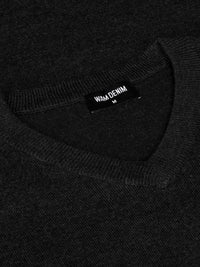 Close-up of the Wam Denim neck label on a black V-neck sweater – Wam Denim.