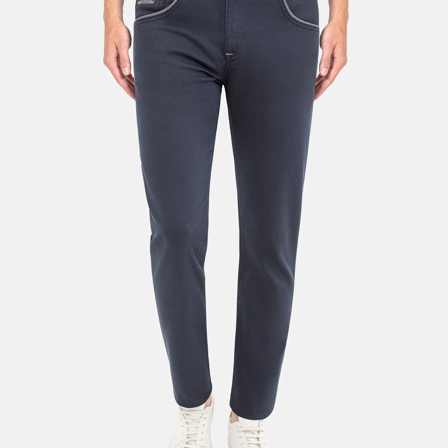 Man wearing dark blue slim-fit jeans with white sneakers. – Wam Denim.