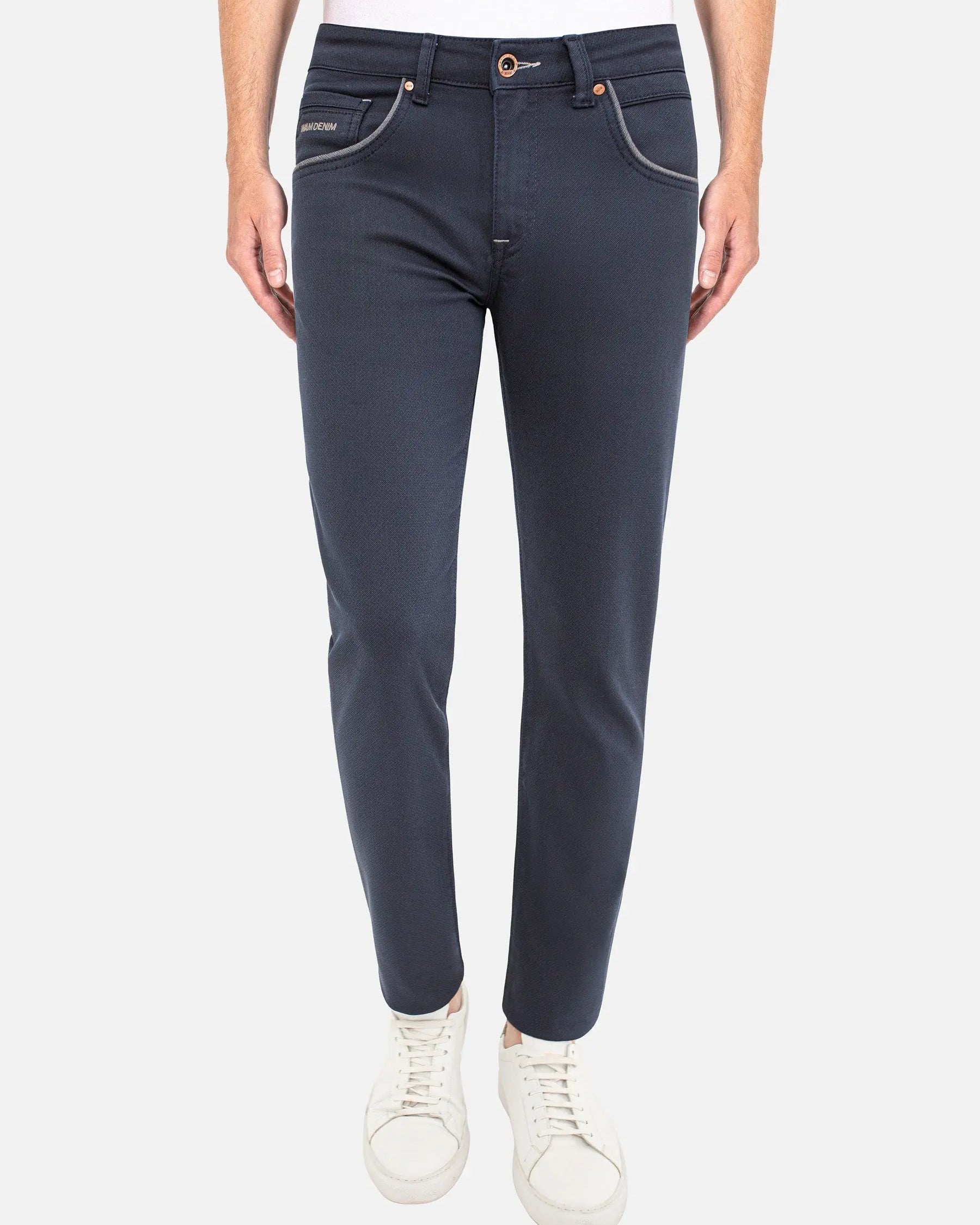 Man wearing dark blue slim-fit jeans with white sneakers. – Wam Denim.