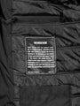 Close-up of the Wam Denim care label inside the black puffer – Wam Denim.