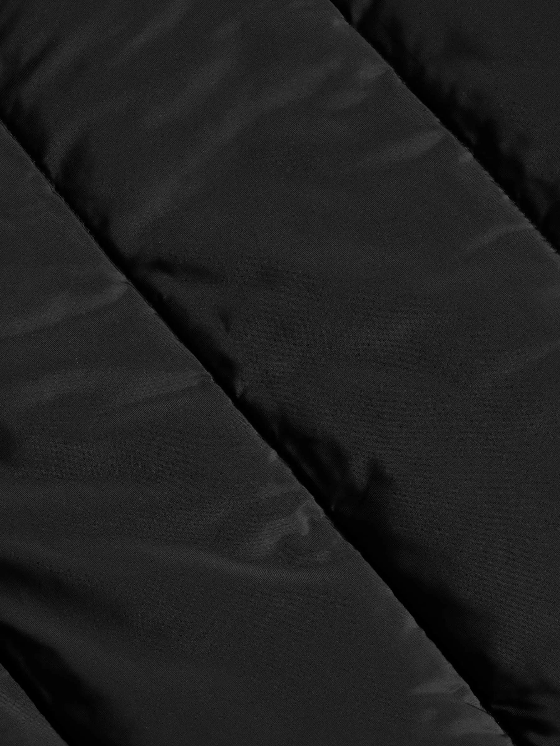 
Close-up texture of the black puffer jacket's quilted nylon fabric – Wam Denim.