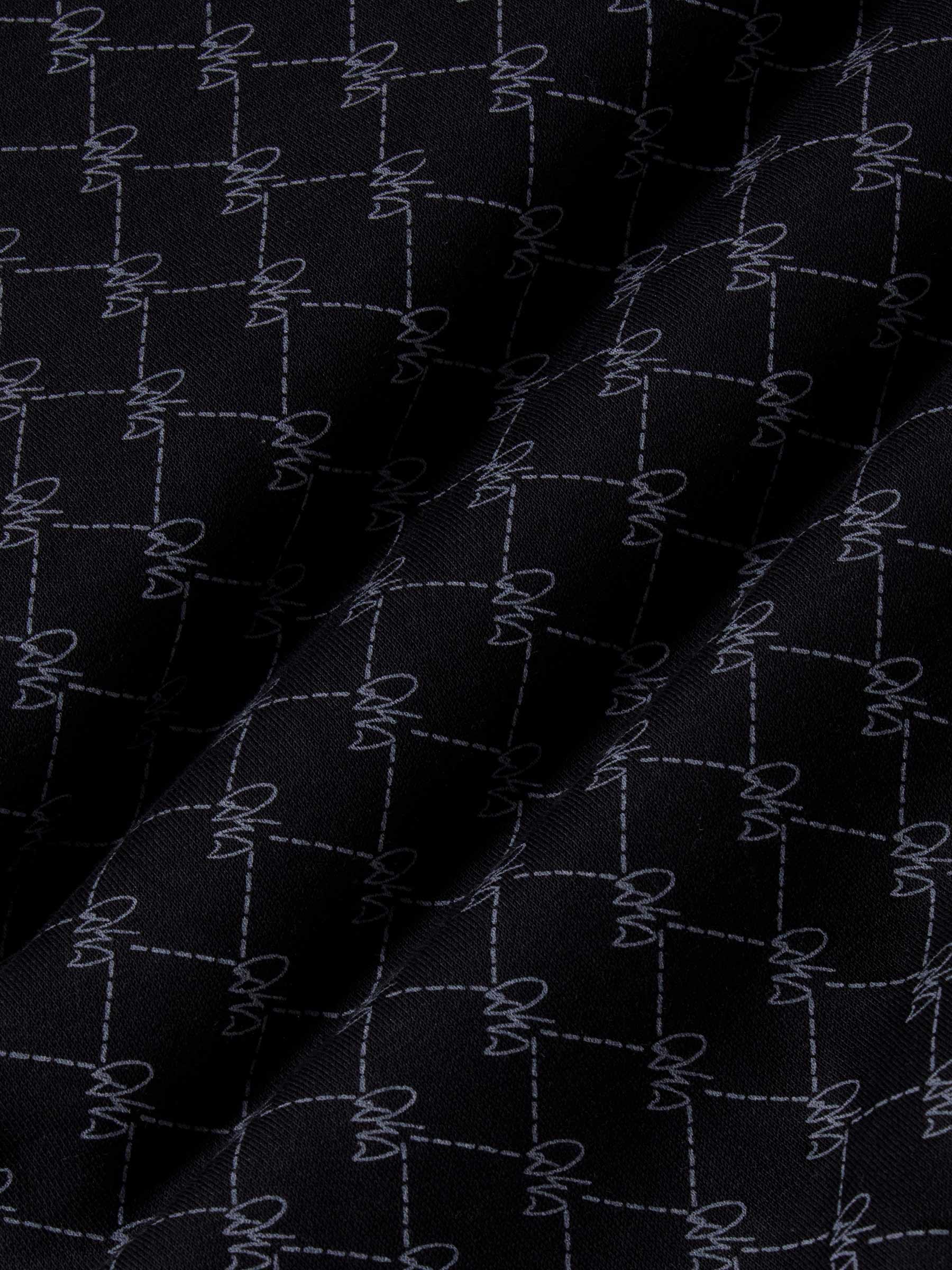 Close-up of black fabric with stitched geometric logo pattern and soft texture – Wam Denim.