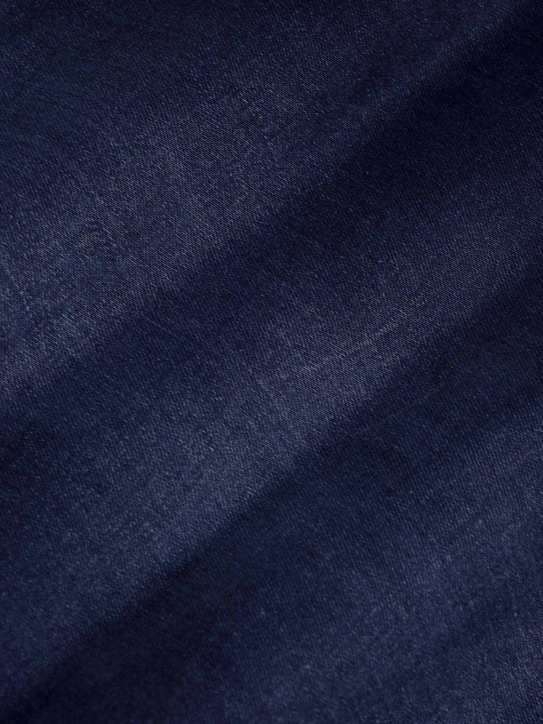 Close-up of dark navy denim fabric texture showing smooth weave and slight fade – Wam Denim.