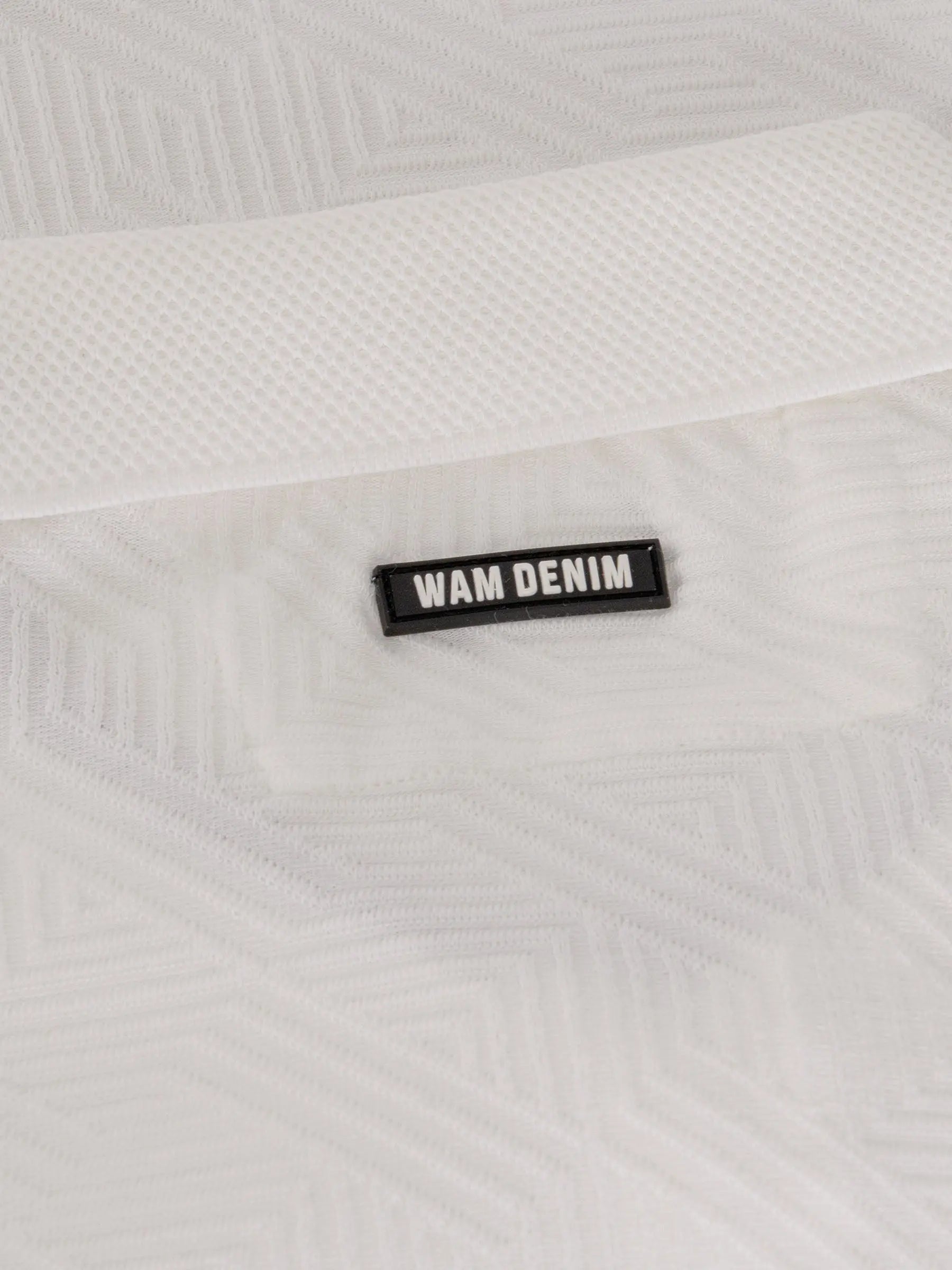 Close-up of the Wam Denim logo on the white polo shirt collar – Wam Denim.