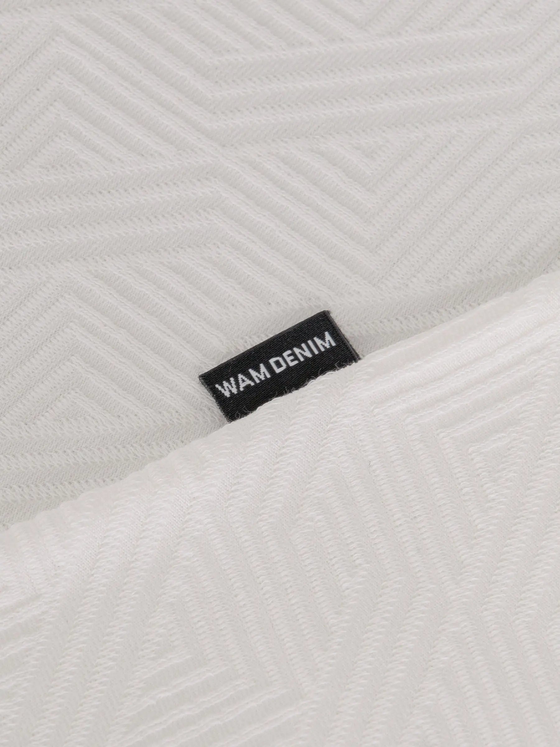 Close-up of the Wam Denim label on the textured white polo – Wam Denim.