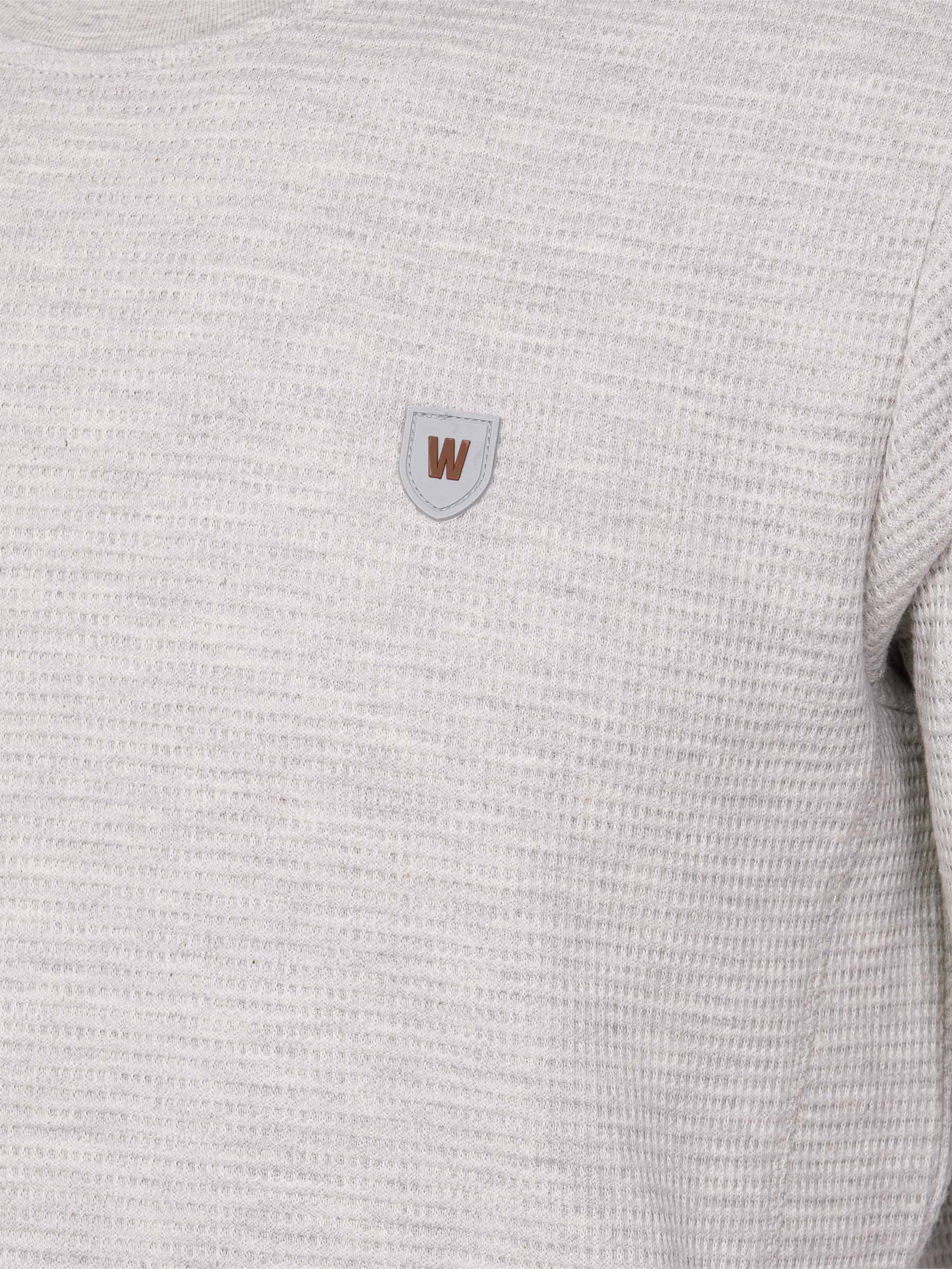 Close-up of light grey textured sweatshirt with brown and grey chest logo patch – Wam Denim.