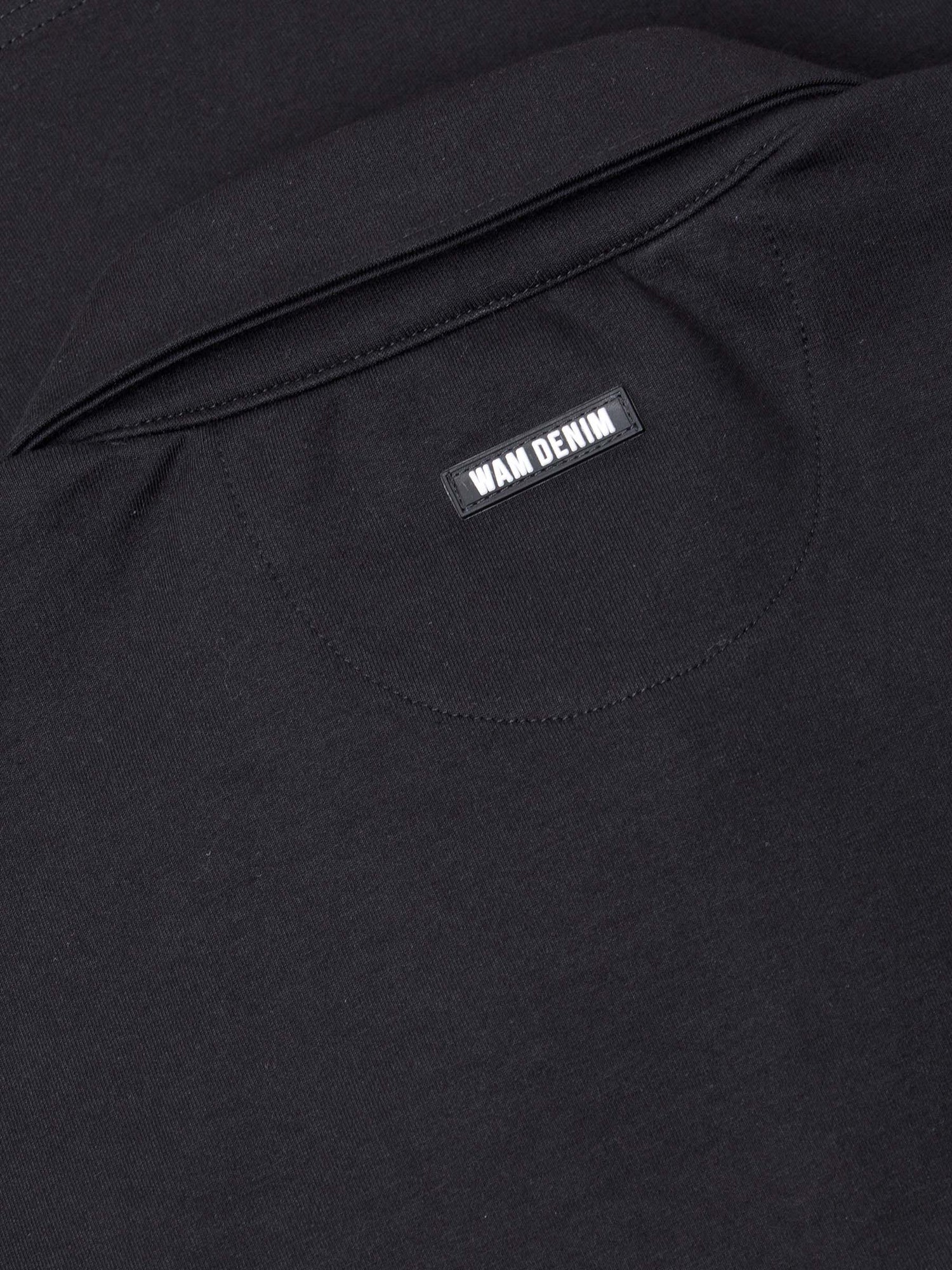 Close-up of The Zeal Black Sweater back collar showing stitched Wam Denim logo label – Wam Denim.