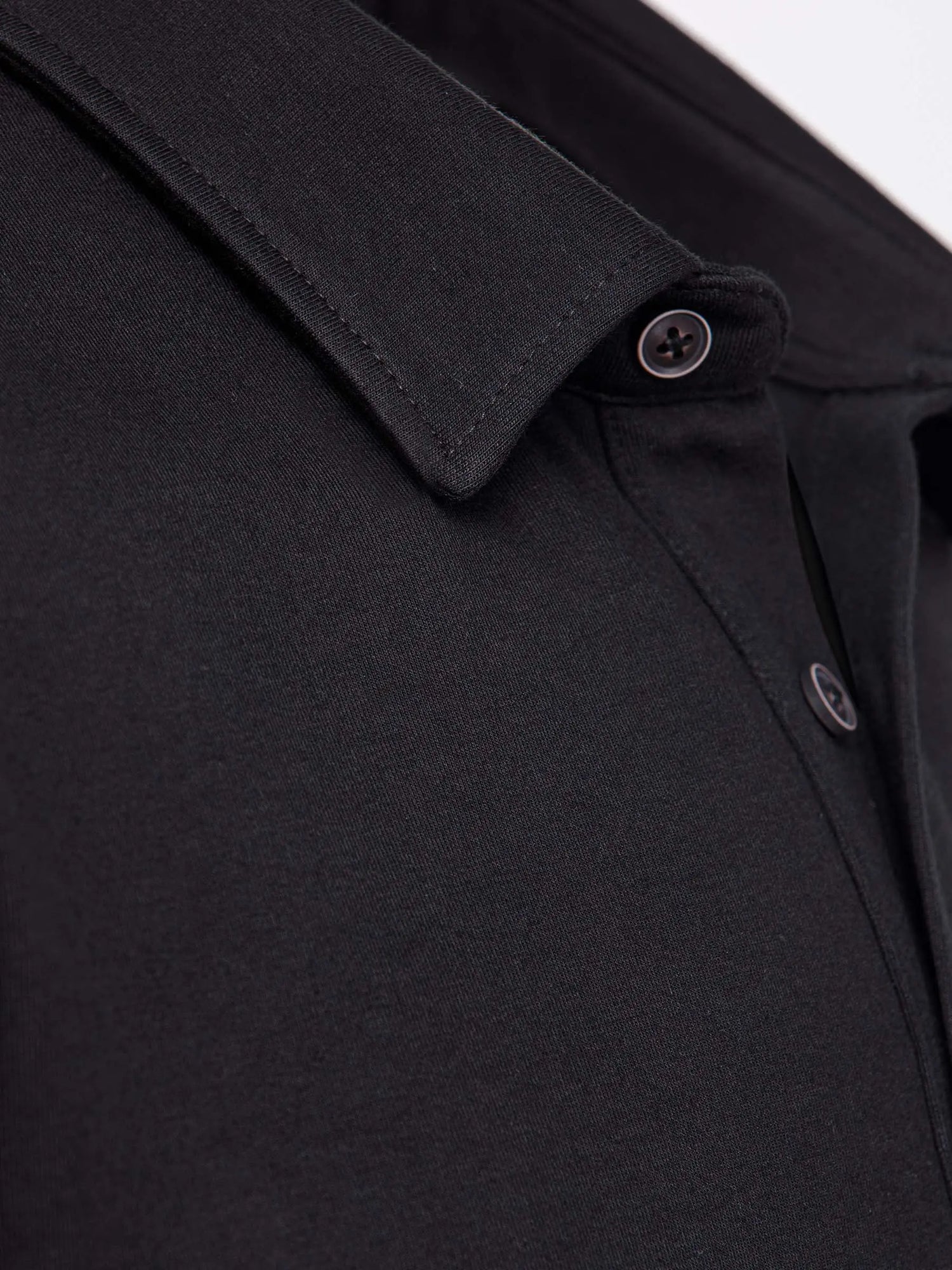 Close-up of The Zeal Black Sweater collar showing fine stitching and button details – Wam Denim.