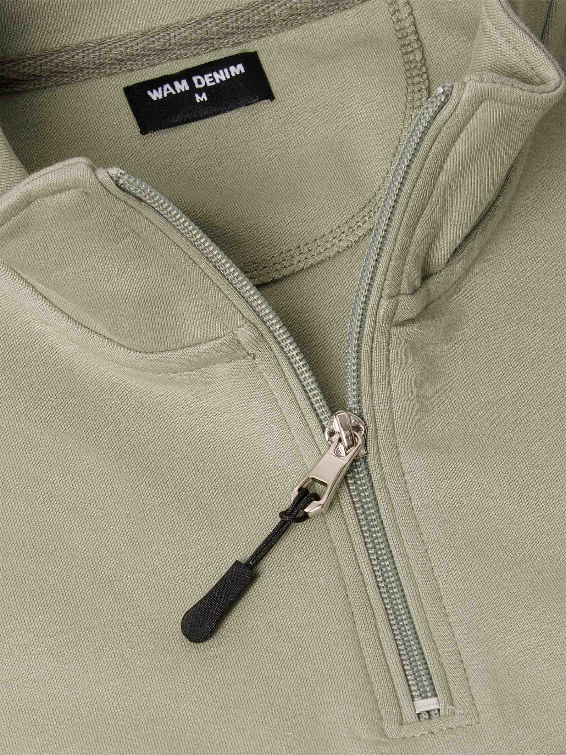 Close-up of a Light Green Sweater with a zipper and 'WAM Denim' label.