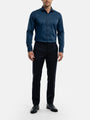 Model wearing petrol blue men’s dress shirt styled with black trousers and formal shoes.