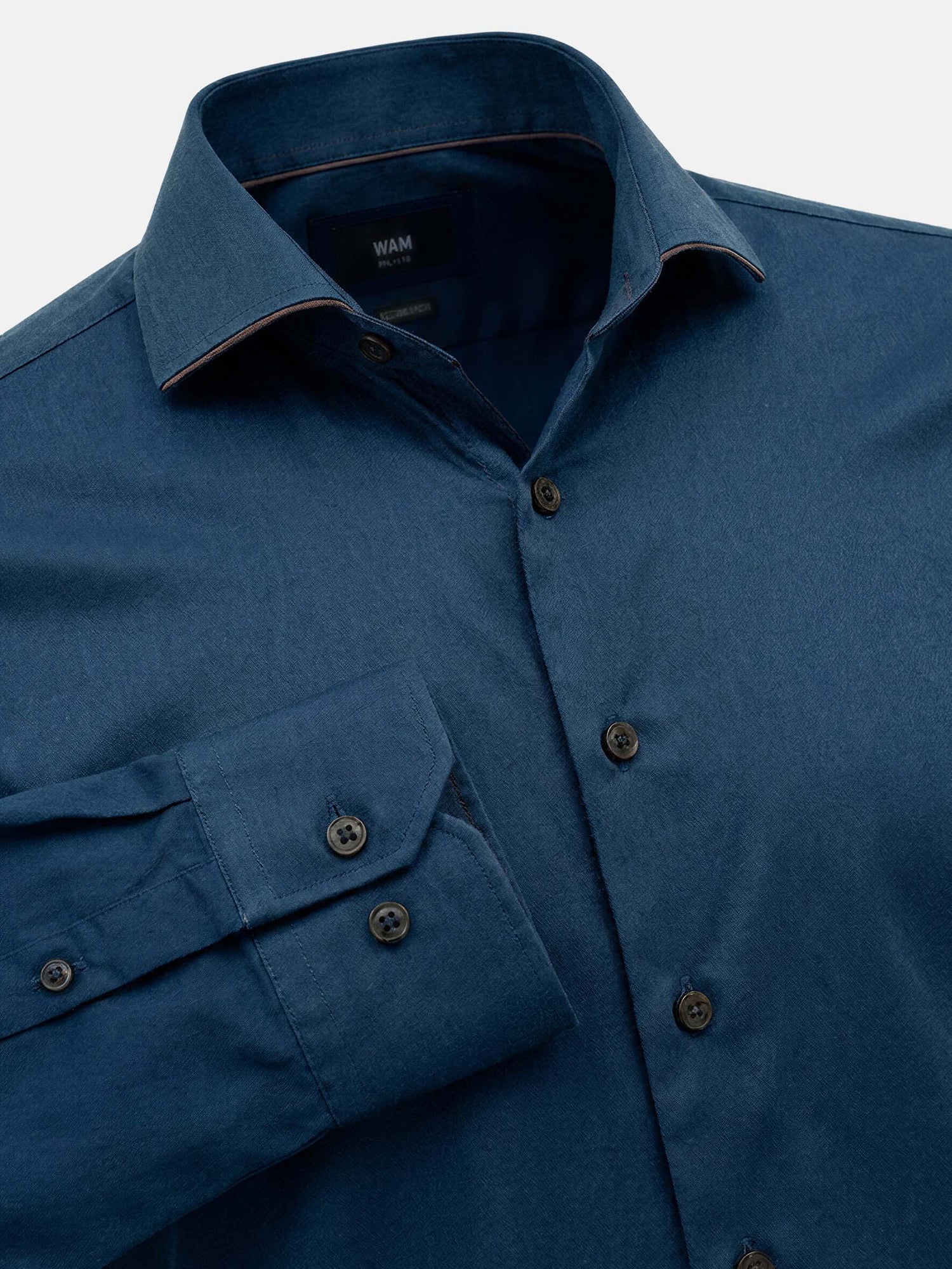 Detail view of petrol blue men’s shirt with sharp collar, button placket, and tailored cuffs.