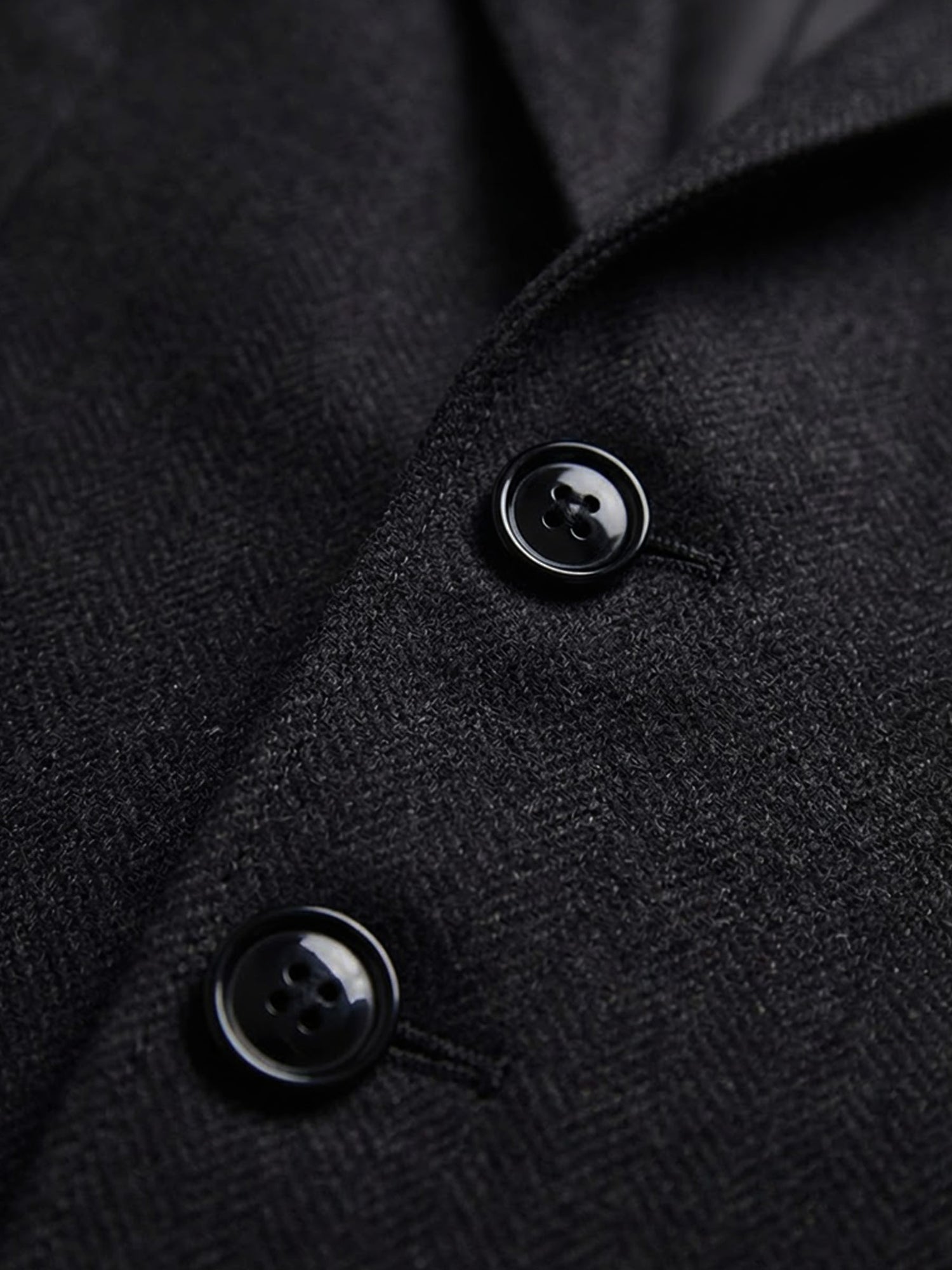 Close-up of black blazer fabric with two-button detail and textured weave.