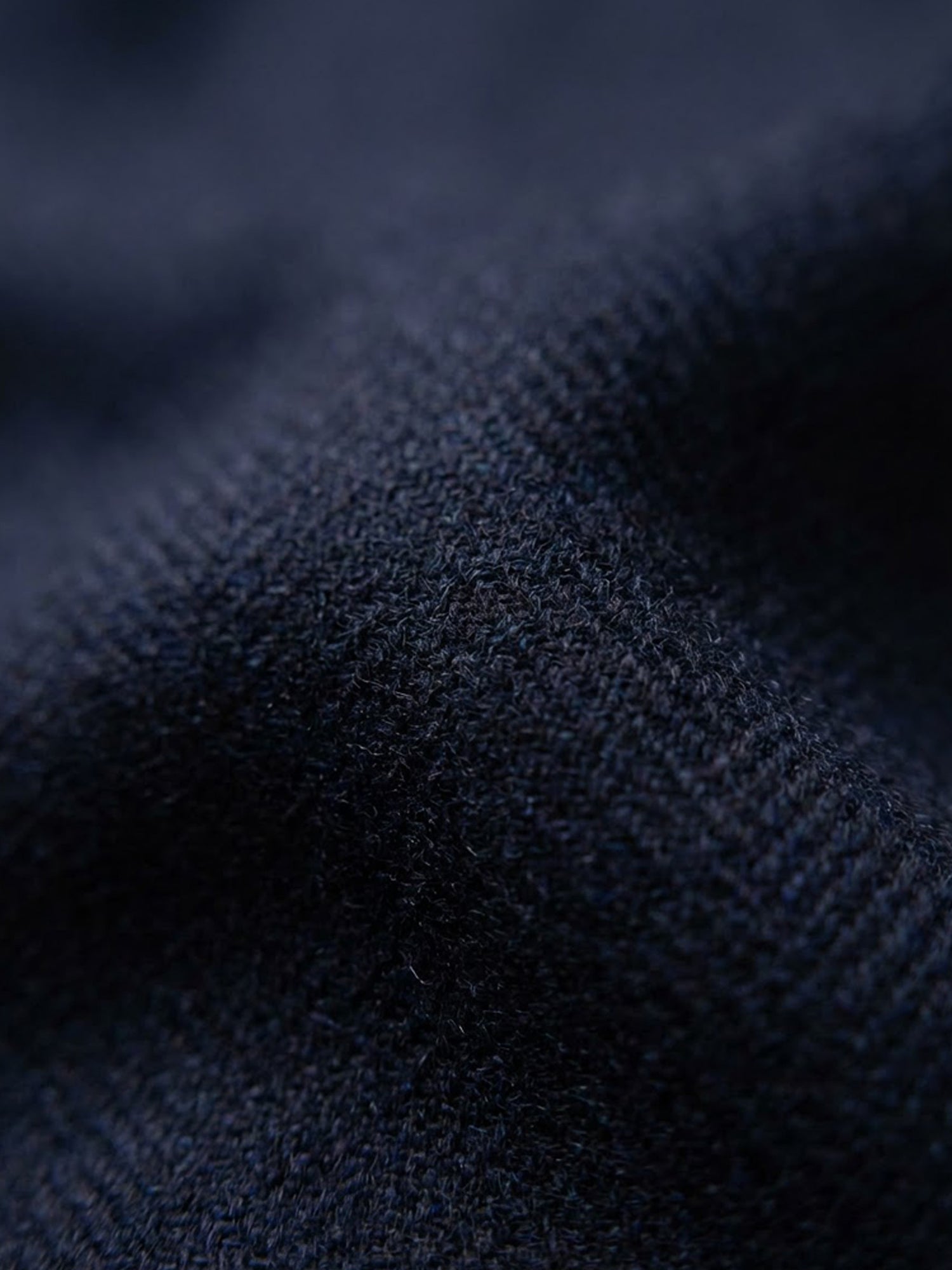 Close-up of navy blazer fabric texture with soft structured finish.