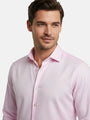 Model wearing pink dress shirt with classic collar, close-up view.