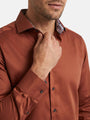 Close-up of light brown men’s shirt with patterned inner collar and button cuff