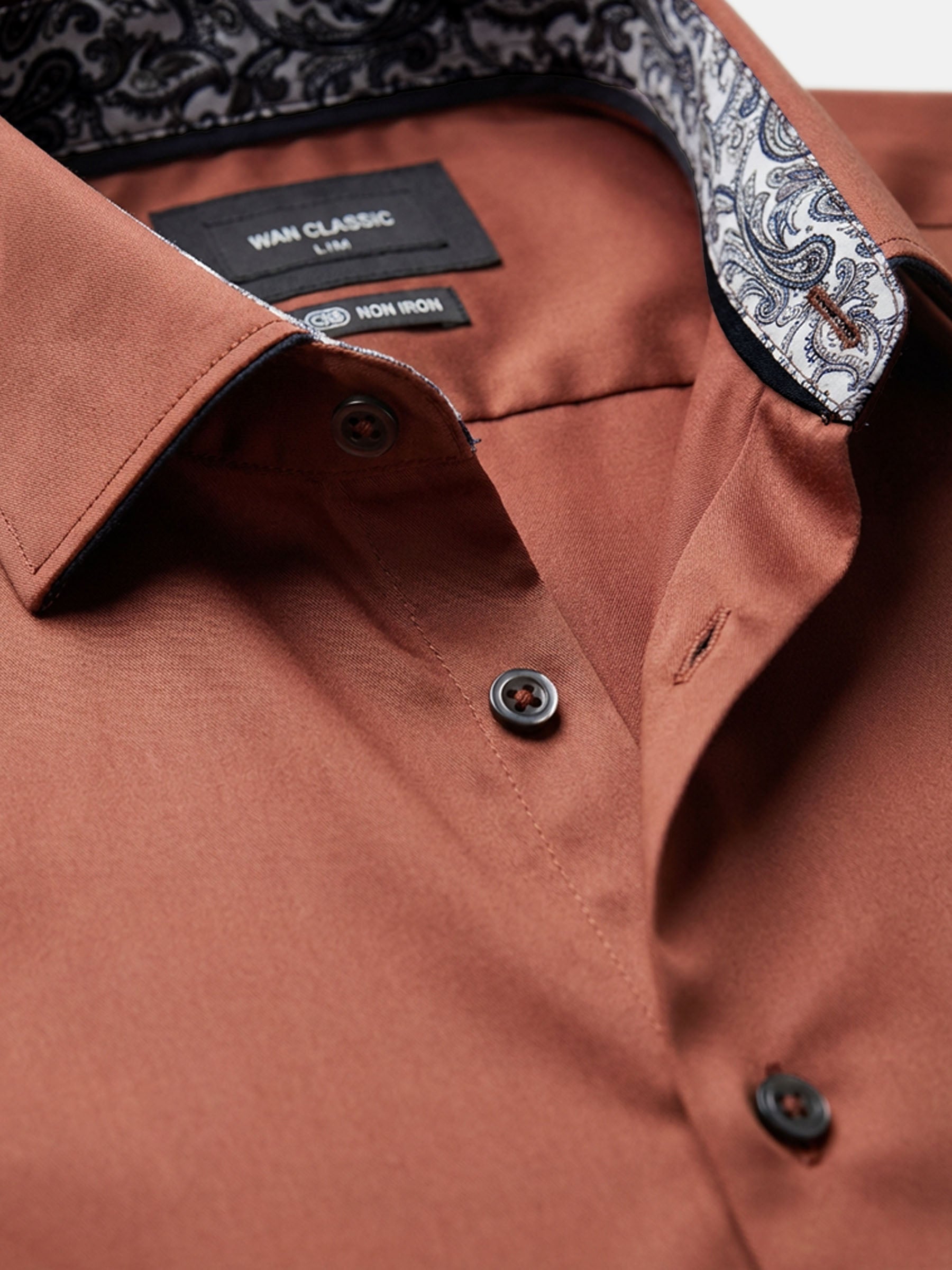 Close-up of light brown men’s shirt collar with patterned lining and premium buttons