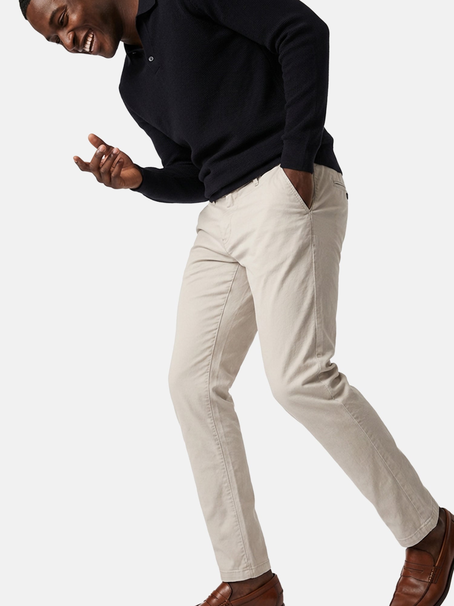 Light beige slim-fit men’s chino pants styled casually with knit sweater and loafers.