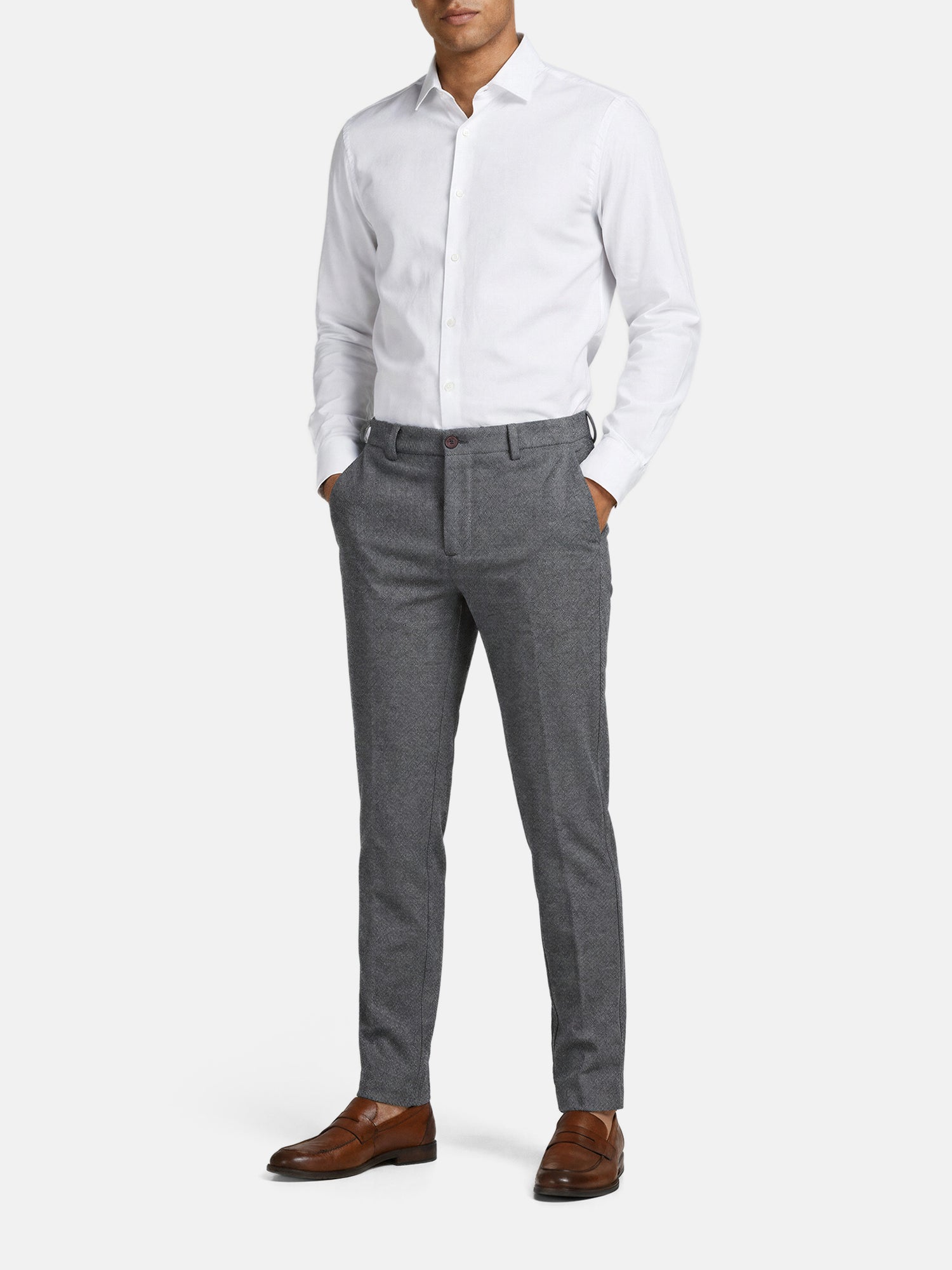 Man wearing grey slim-fit pantalon styled with a white shirt and brown dress shoes.