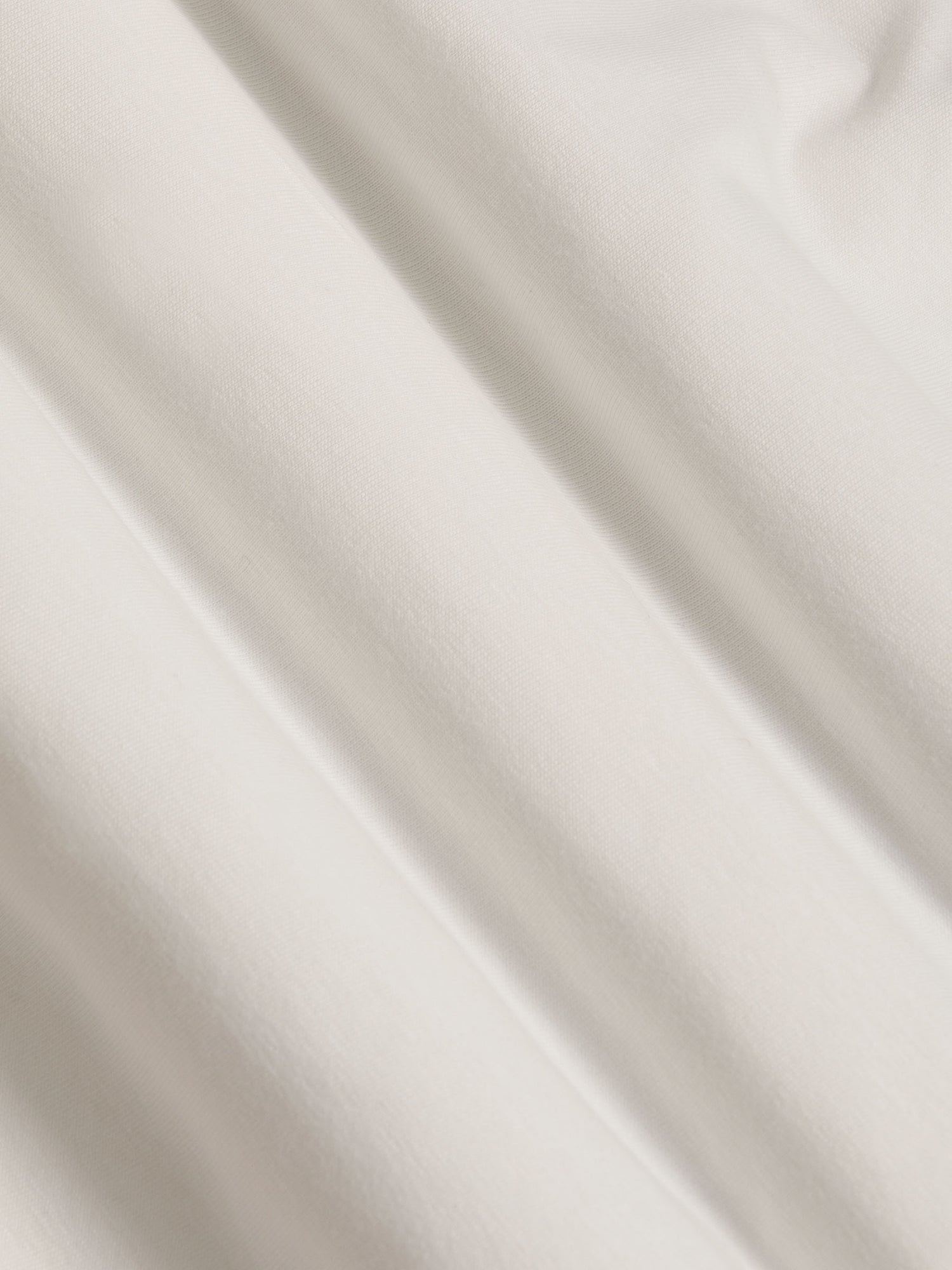Close-up of off-white cotton T-shirt fabric showing soft, smooth texture