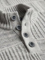 Close-up of light grey knit sweater’s ribbed collar and button placket detailing.