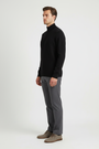 Side view of a male model wearing a black fine-knit quarter-zip sweater